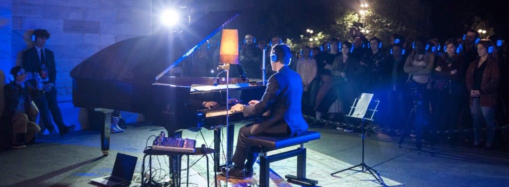 Pianist på konsert, publik med hörlurar